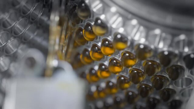 Yellow gel capsules in an automatic machine. Production of dietary supplements and medicines. Tablets with vitamins and minerals for a healthy lifestyle. Omega 3 or fish oil is spinning.