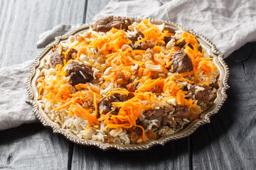 Traditional oriental pilaf with lamb topped with caramelized carrots, raisins and nuts close-up on...