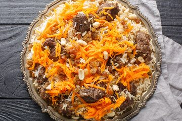 Kabuli pulao luxurious pilaf Afghan national dish closeup on the plate on the wooden table....