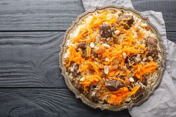Traditional oriental pilaf with lamb topped with caramelized carrots, raisins and nuts close-up on...