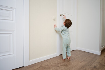 Little baby opens the door. Child pulls the door handle with the lock closed. Kid aged two years