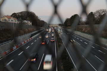 フェンスを通して見る東名高速道路の大和トンネル付近の夕景