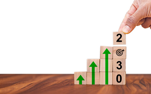 Business growth concept in 2030. Business goals and achievement. Sustainable development. Wooden cubes inscripted 2030 and growth icons on smart background. Positive indicators and trend concept