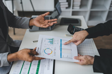 Businessman consultant, teamwork is talking Plan to analyze the cost graph. Investment and market data on charts and documents on office desk.