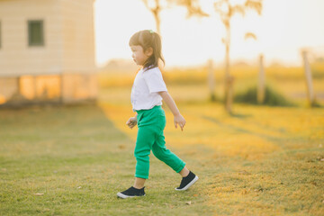 relaxing style of asian baby cute girl walking play on a the outdoor grass ground with happy time on evening time