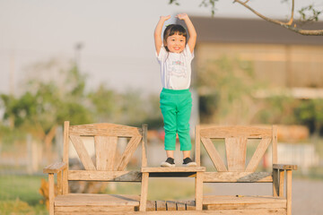 relaxing style of asian baby cute girl Jump play on a the table wood in outdoor grass ground with happy time on evening time