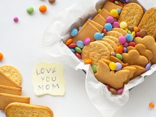 Assorted cookies and candies in the basket with Love you mom note. Mothers Day concept. Handmade...