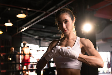 Beautiful female preparing bandages fighter trains in boxing  at gym.Looking at camera.
