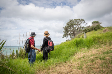 Fototapeta na wymiar Couple holding hands, enjoying stunning views of Hauraki Gulf. Long Bay coastal walk. Auckland.
