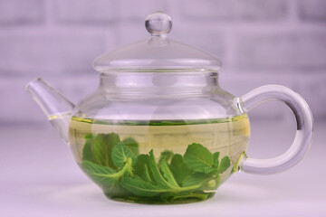 Teapot with mint tea on a white background.
