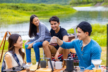 Group of Asian Man and woman friends having breakfast and making brewed coffee at camp in the morning. People enjoy and fun outdoor lifestyle travel nature and camping together on summer vacation.