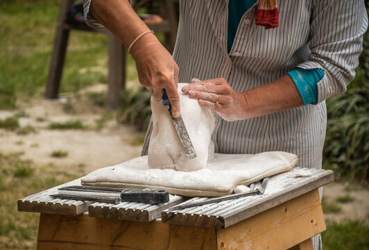 Woman carving a stone during an outdoor sculpture lesson or class in the botanical garden of San Sebastiano da Po Castle near Torino, Piemonte region, Italy