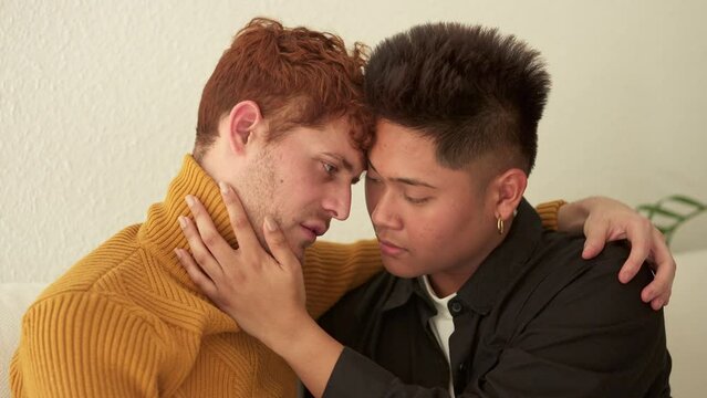 Gay couple about to kiss sitting on the sofa