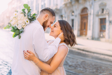 Fototapeta premium happy bride and groom embrace while walking through the old city, the couple looks at each other and smiles