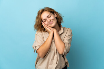 Young Georgian woman isolated on blue background making sleep gesture in dorable expression