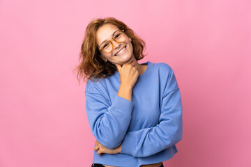 Young Georgian woman isolated on pink background with glasses and smiling