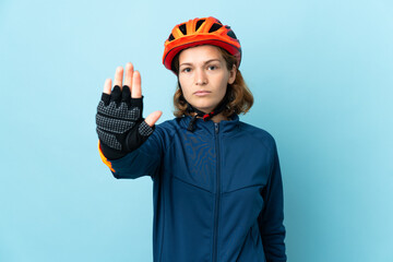 Young cyclist woman isolated on blue background making stop gesture