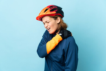 Young cyclist woman isolated on blue background suffering from pain in shoulder for having made an effort