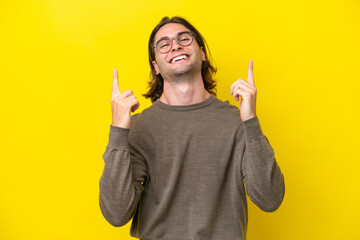 Caucasian handsome man isolated on yellow background pointing up a great idea