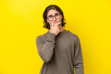 Caucasian handsome man isolated on yellow background having doubts