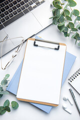 Modern white office desk table with laptop, notebook and other supplies.