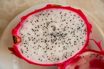 Pitaya (dragon fruit) cut in half with finer and black seeds showing