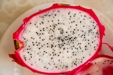 Pitaya (dragon fruit) cut in half with finer and black seeds showing