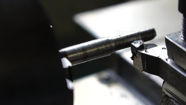 Close-up lathe machine operation by cutting the metal tube. vintage lathe machine tool operates with metal detail under mature worker control in old production plant workshop. Slow motion