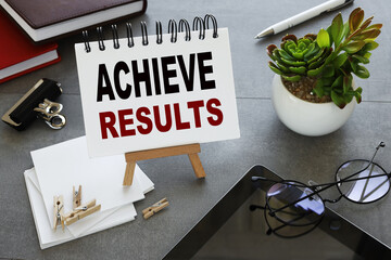 ACHIEVE RESULTS. notebook with text on stand