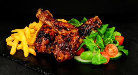 Barbecued chicken drumstick leg meal with French fries and salad