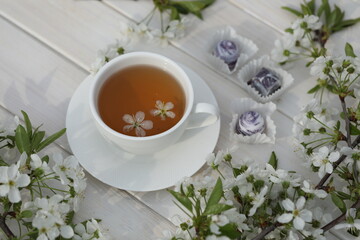 cup of tea with cherry blossom decoration on white wooden background.