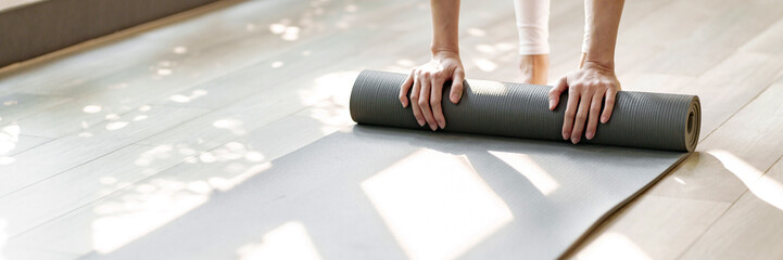 Fitness woman rolling Yoga mat before training, Healthy lifestyle.