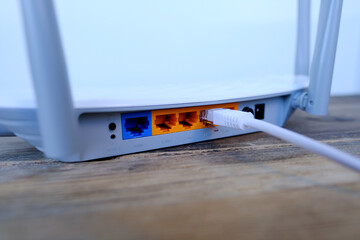 white cable is plugged into the port of Wi-Fi router, modern wireless Router with four...