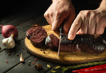 The chef cuts blood sausage with a knife on a cutting board before serving for lunch. National dish...