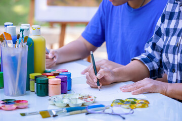 A female teacher is teaching teen student to sketch picture at school art club, teacher help teenage boy practicing school art project