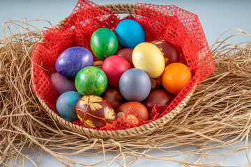 Multicolored Easter eggs in a basket over straws. Pastel colored Easter eggs.