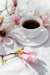 Fototapeta na wymiar cup of coffee with milk and spring flowers magnolia branches against a white background. spring mood. good morning concept