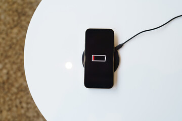 Charging mobile phone battery with wireless charging device in the table. Smartphone charging on a...