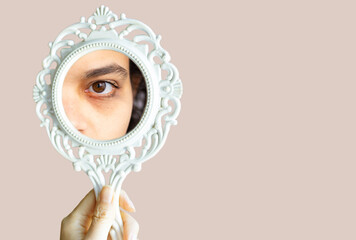 Fototapeta Sleepless young woman looking her face in the mirror and worry about dark circles under eyes. Girl showing eye bag through mirror. obraz