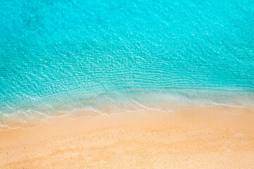 Summer seascape beautiful waves, blue sea water in sunny day. Top view from drone. Relax sea aerial view amazing tropical nature background. Tranquil bright sea waves splashing beach sand sunset light