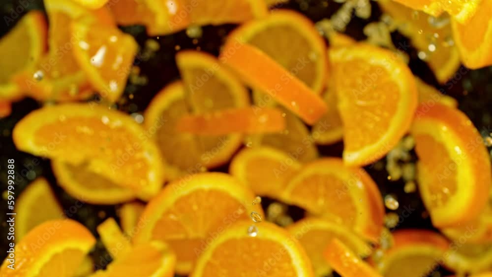 Poster Super slow motion of flying orange slices with water on black background. Filmed on high speed cinema camera, 1000 fps. Camera placed on high speed cine bot, tracking the object. Speed ramp effect.