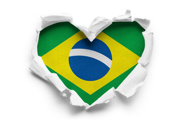 Heart shaped hole torn through paper, showing satin texture of flag of Brasil, cut out