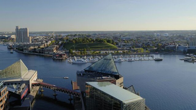 Aerial Panning Shot Of Boats Moored At Harbor While Buildings In Background At City - Baltimore, Maryland