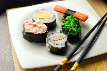 Sushi served in a white plate with sauce.