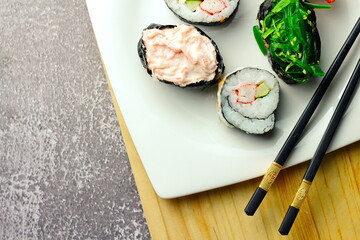 Sushi served in a white plate with sauce.