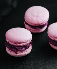 Obraz na płótnie Canvas Pink macarons with chocolate filling on black stone