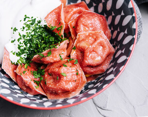 Tasty dumplings with lamb with vegetable dressing and sour cream