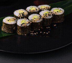 Sushi rolls maki with rice and avocado on a bamboo leaf