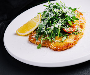 Traditional chicken schnitzel with arugula and lemon