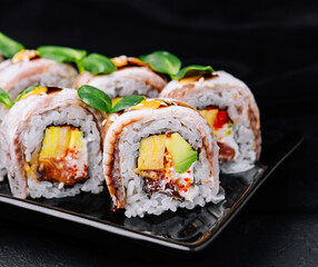 Eel sushi rolls on black plate